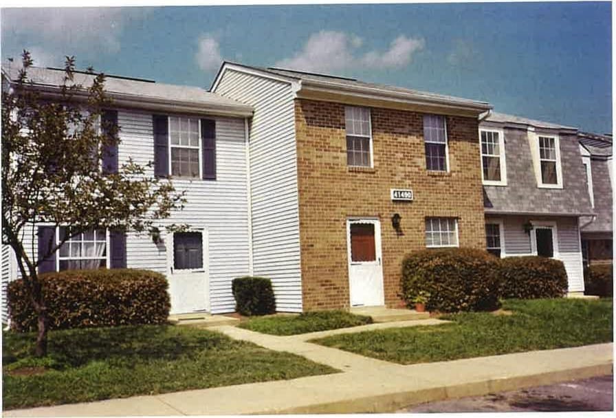 A row of two-story Leonard's Freehold townhouses in brick and light siding under a blue sky