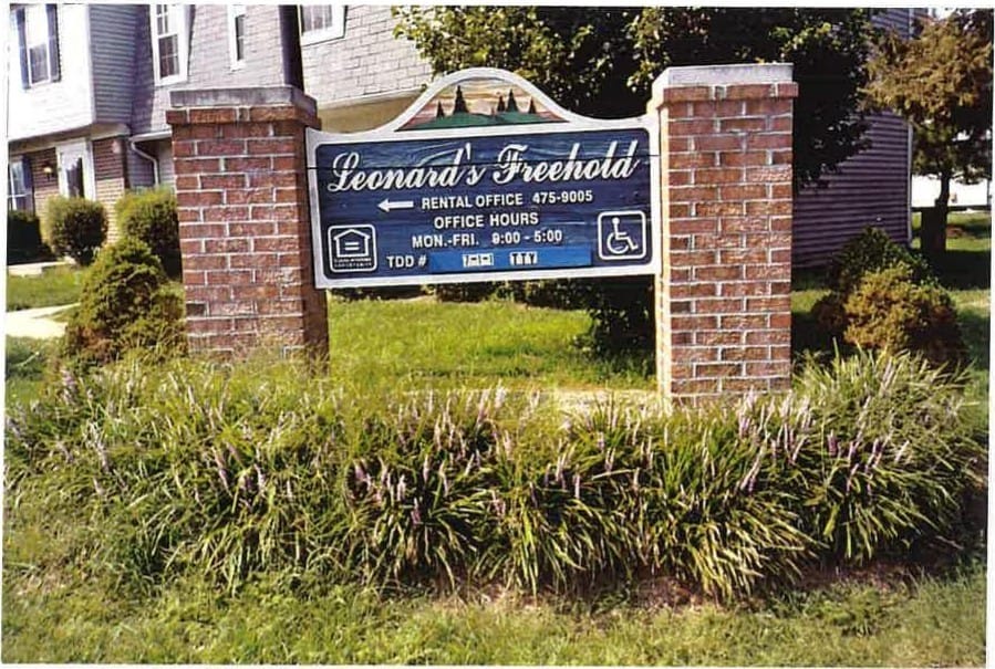 The Leonard's Freehold entrance sign on brick pillars, with townhouses behind